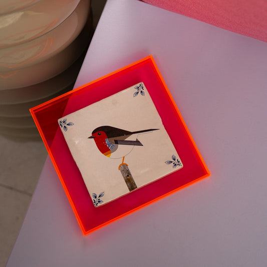 Roodborstje in geometrische vormen op keramiek gedrukt in een neon roze tegel